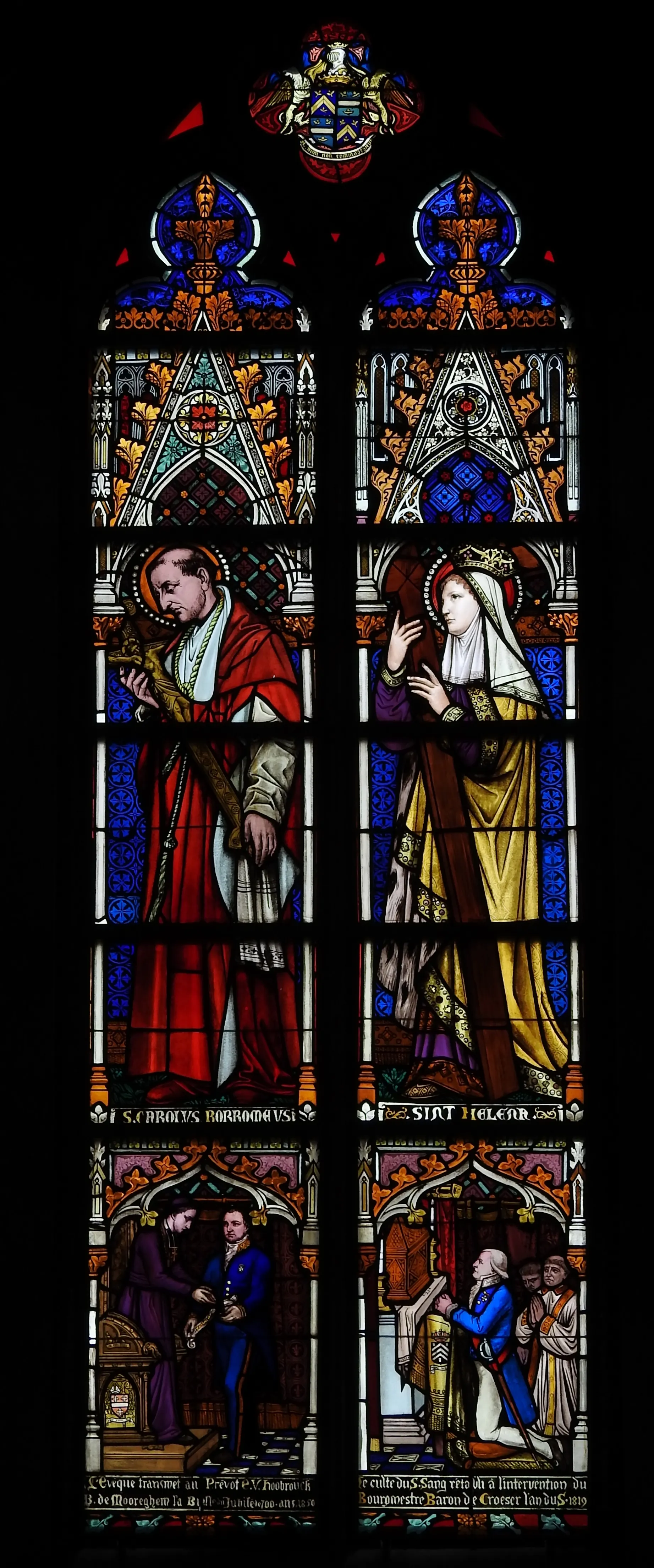 Tall stained glass window showing Saint Charles Borromeo in red robes holding a crozier and Saint Helena in a golden dress with a crown, with narrative scenes at the bottom and a coat of arms above.