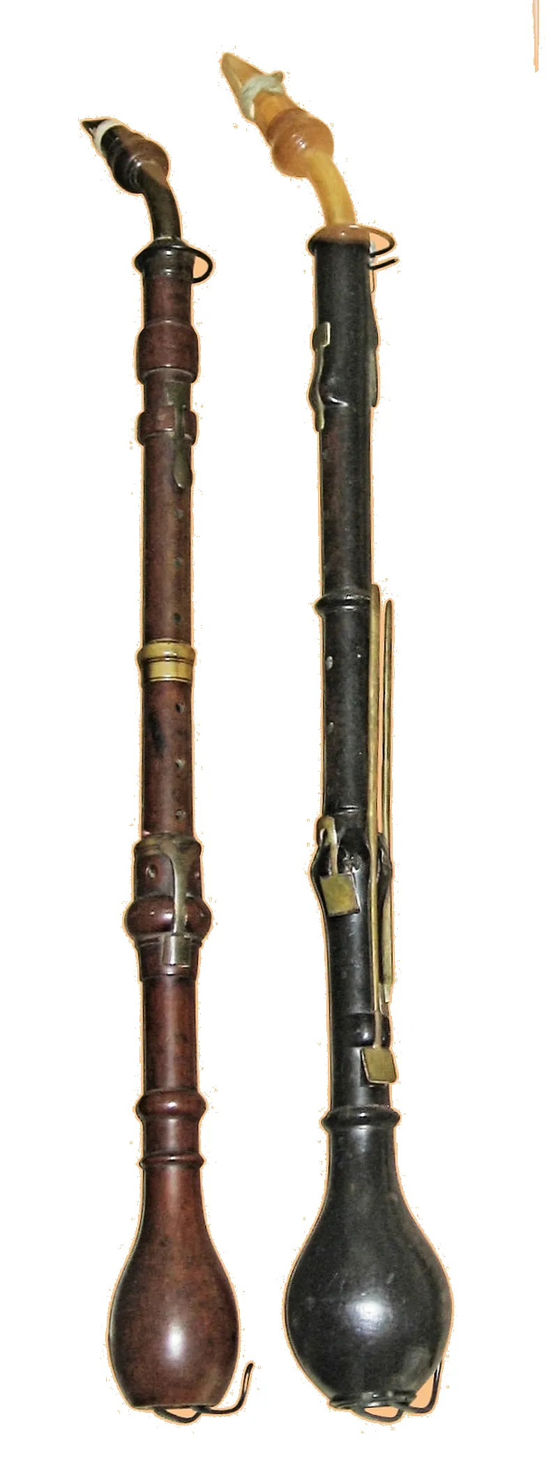 Two historical clarinettes d'amour woodwind instruments with curved metal mouthpieces and brass keys displayed against white background