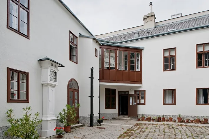 biały budynek z brązowymi oknami i wejściem na dziedziniec