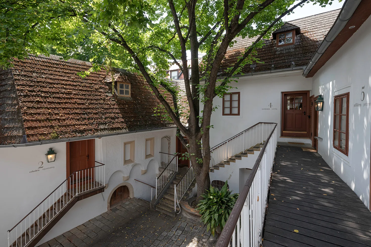 Patios con edificios blancos, tejado de tejas, escalera de madera y árboles en la Casa de Beethoven