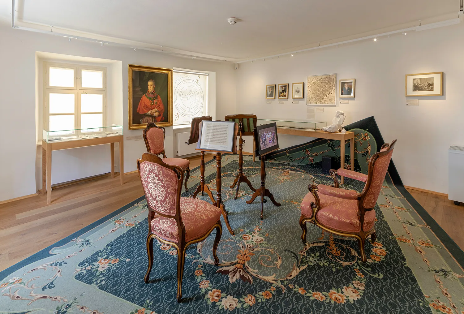 Interior de la Casa de Beethoven con sillas ornamentadas, un atril y obras de arte enmarcadas en las paredes