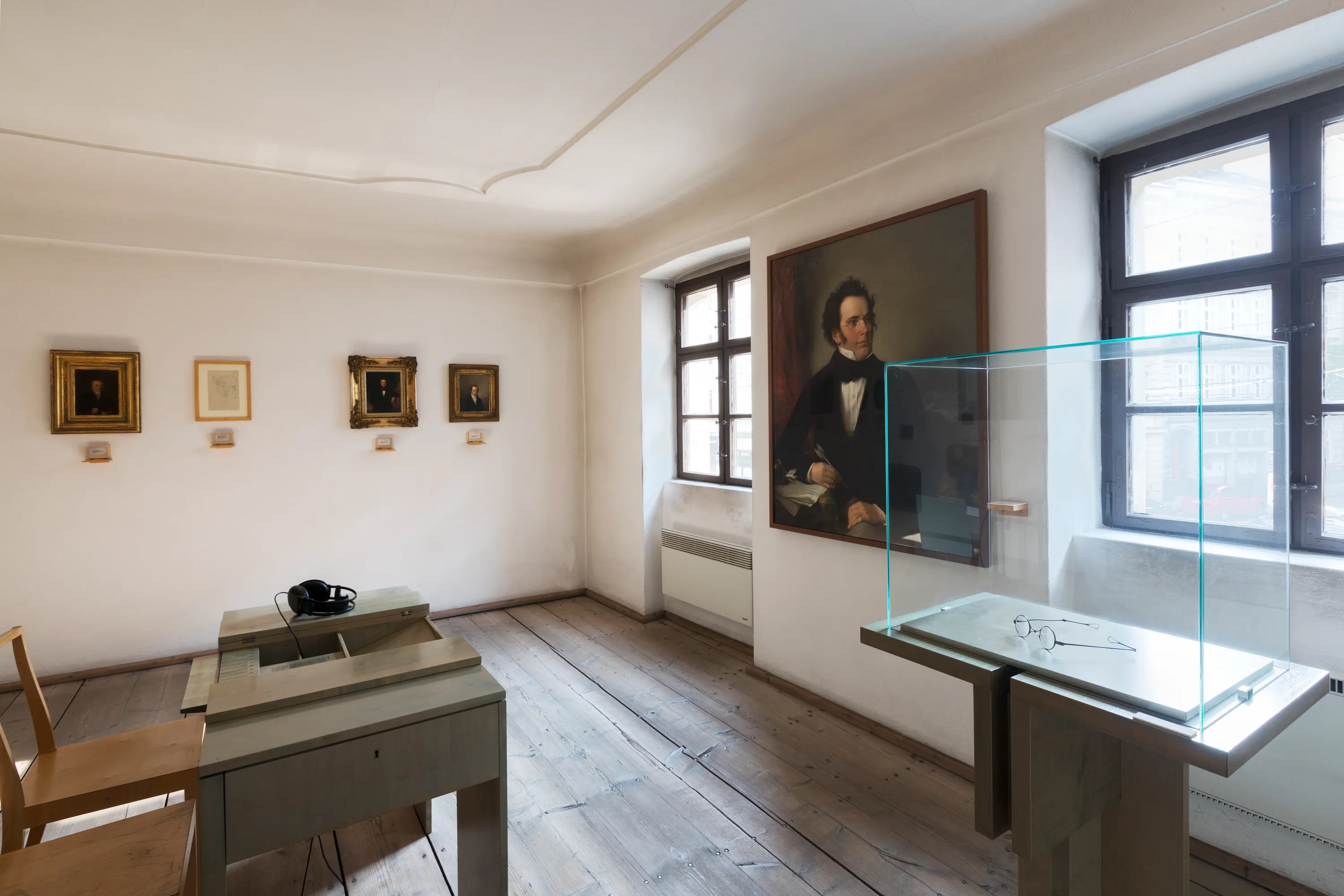 Interior room with a portrait of Beethoven, framed artworks, and display cases on wooden floors