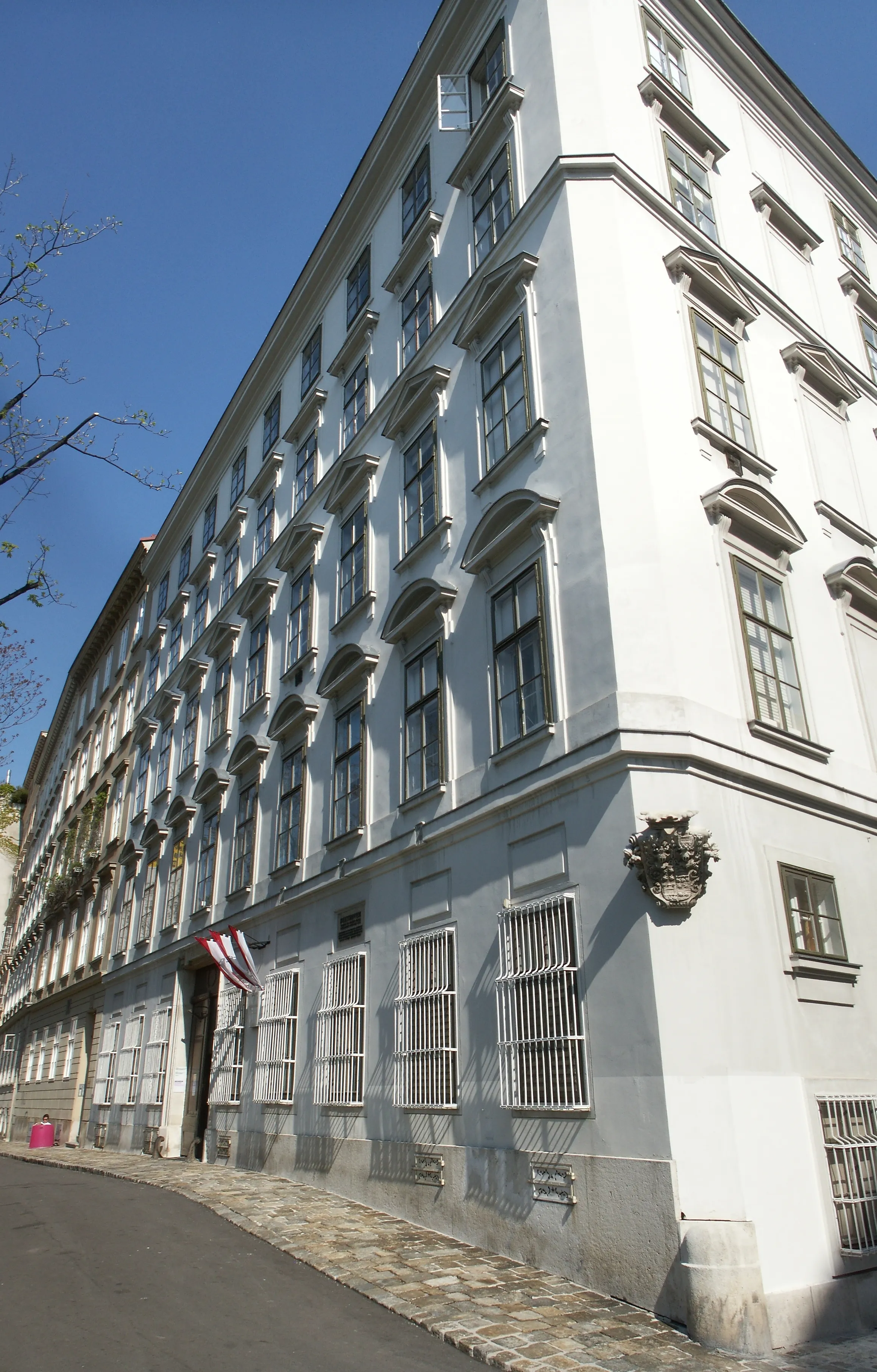 White historic building with multiple windows and a flag near the entrance under a blue sky