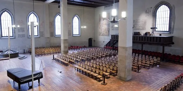 Interior de la Capilla de Belén con bancos de madera, ventanas arqueadas y pilares de piedra