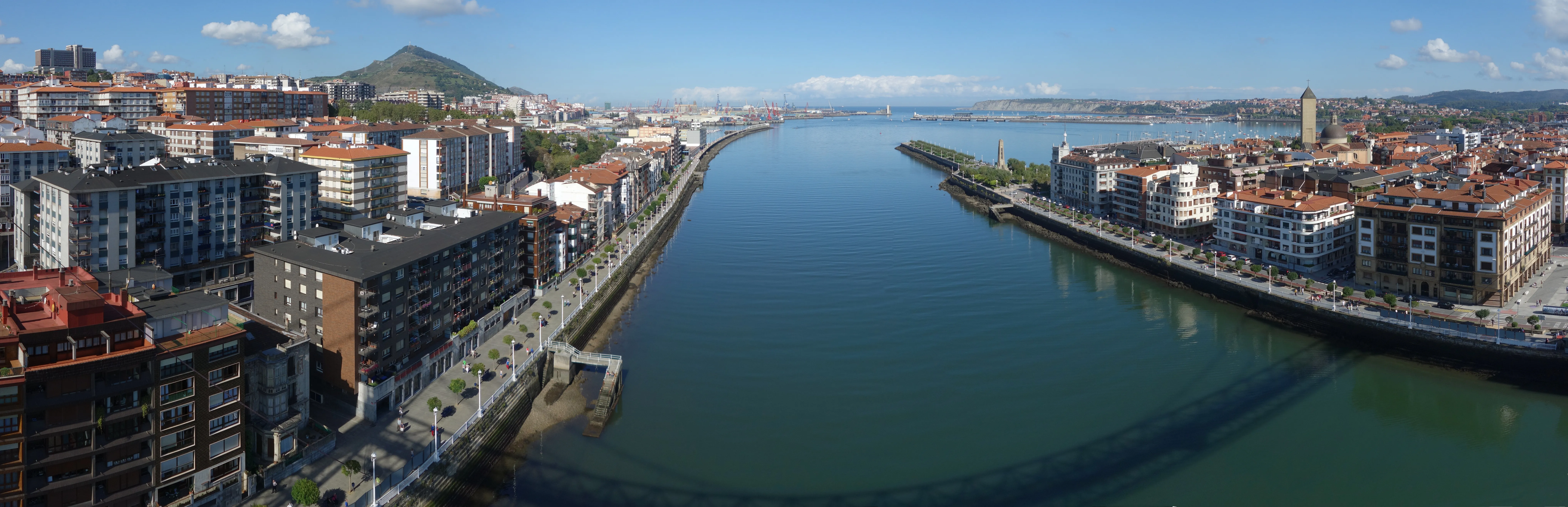 Vista panorámica de la ría del Nervión con Portugalete a la izquierda y Getxo a la derecha, con el Puente Bizkaia visible cruzando el agua a lo lejos.