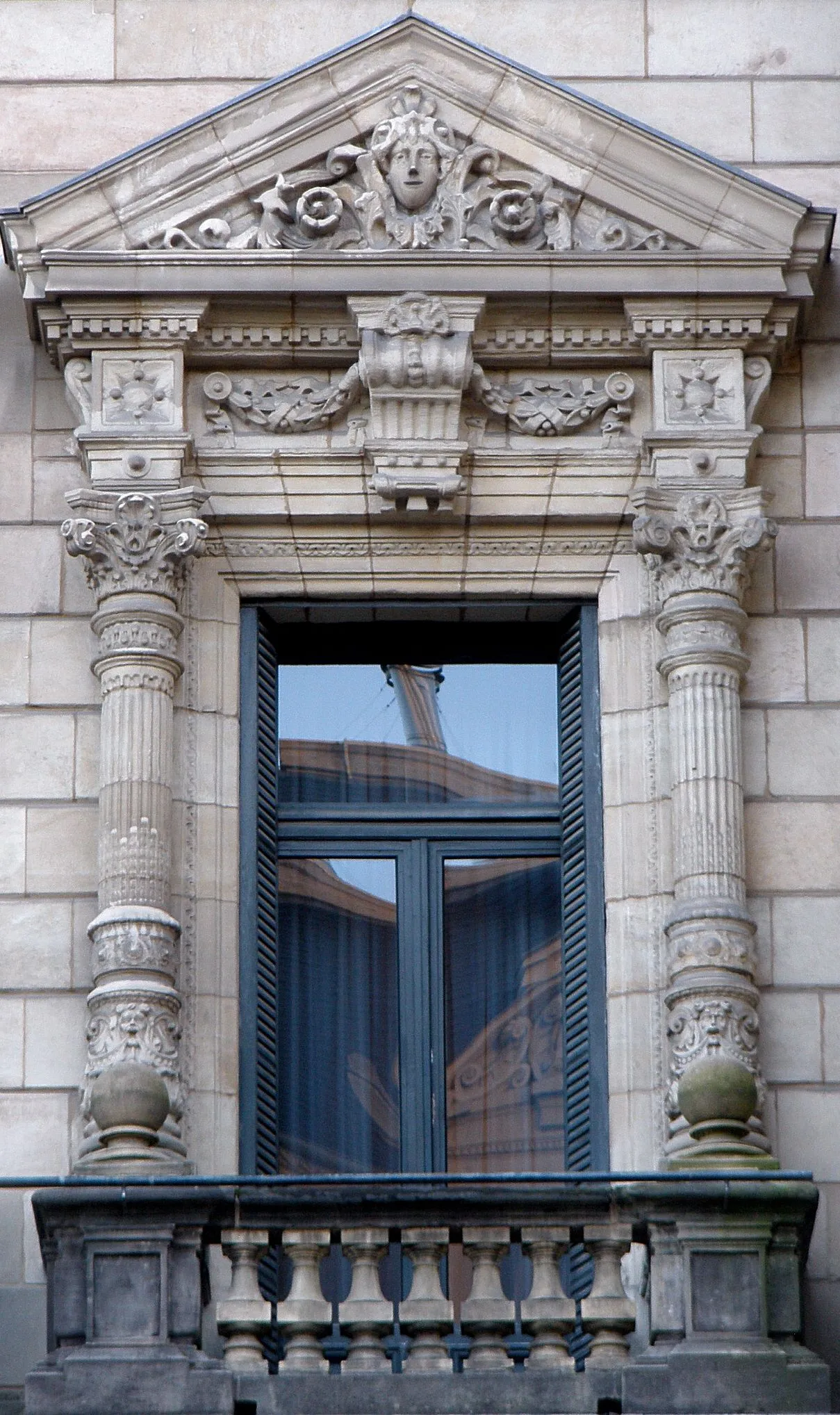 Ornate stone window surround with a triangular pediment, carved face, fluted columns, and a small balcony on the facade of the Bizkaia Provincial Council Palace.