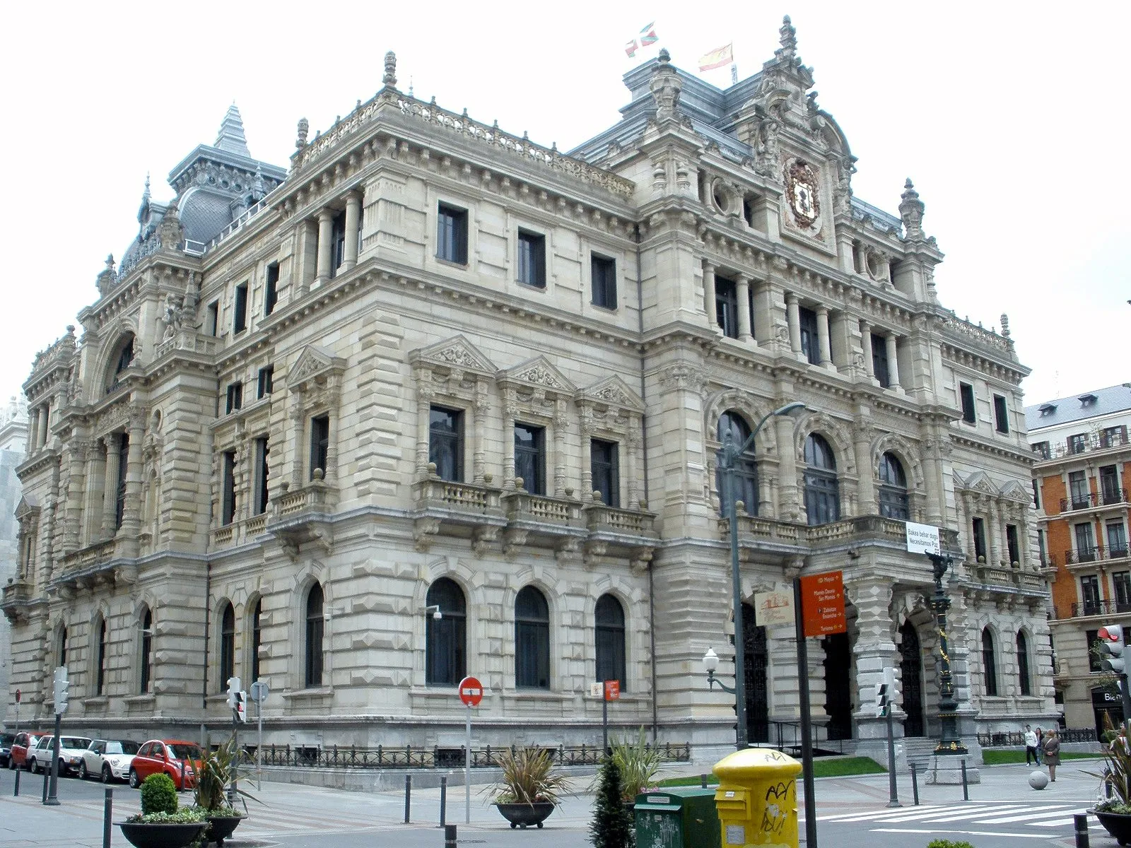 Ornate eclectic stone facade of the Bizkaia Provincial Council Palace in Bilbao, showing arched windows, decorative stonework, and a coat of arms on the upper facade