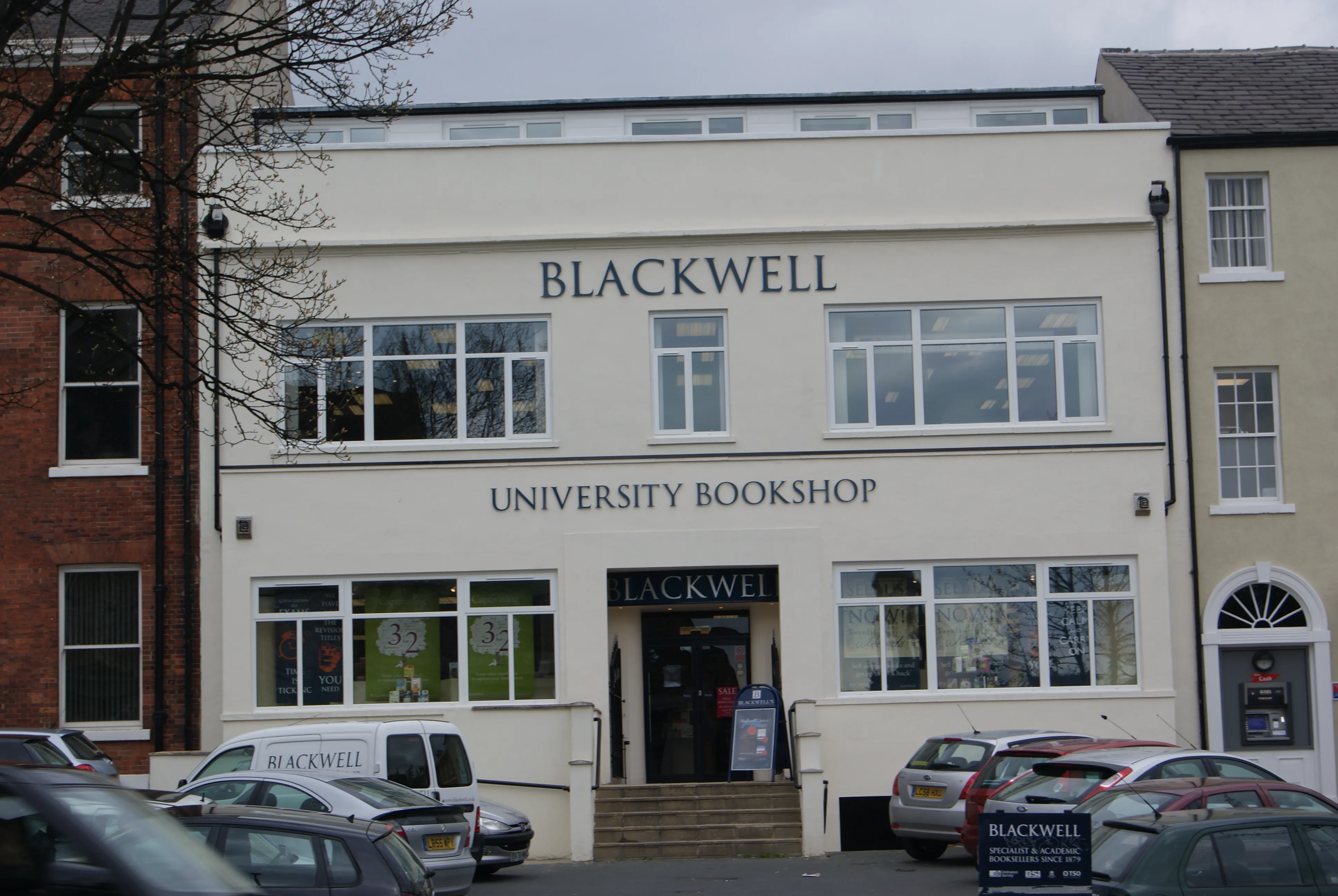 Biała fasada Blackwell University Bookshop z dużym szyldem nad wejściem, zaparkowane samochody przed budynkiem