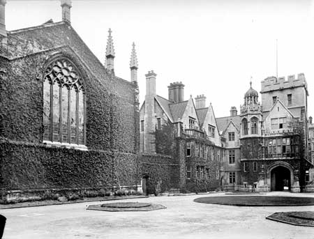 Czarno-białe zdjęcie dziedzińca New Quad w Brasenose College, przedstawiające porośnięte bluszczem gotyckie budynki z dużym łukowym oknem, wieloma kominami oraz dziedziniec z okrągłymi rabatami kwiatowymi.