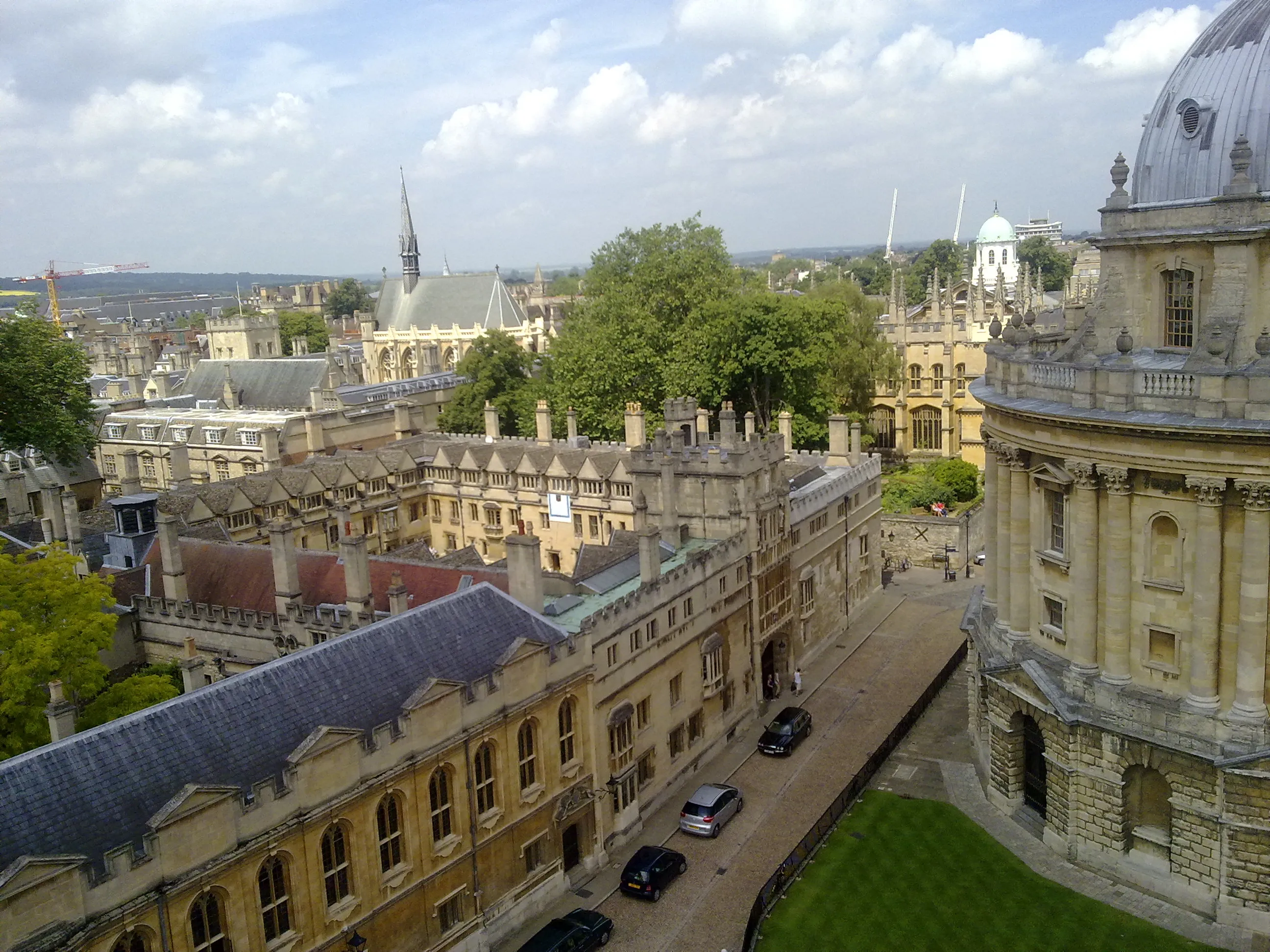 Widok z lotu ptaka na dziedziniec Brasenose College i otaczające go kamienne budynki w Oksfordzie, z kopułą Radcliffe Camera po prawej stronie i ulicą z samochodami poniżej.