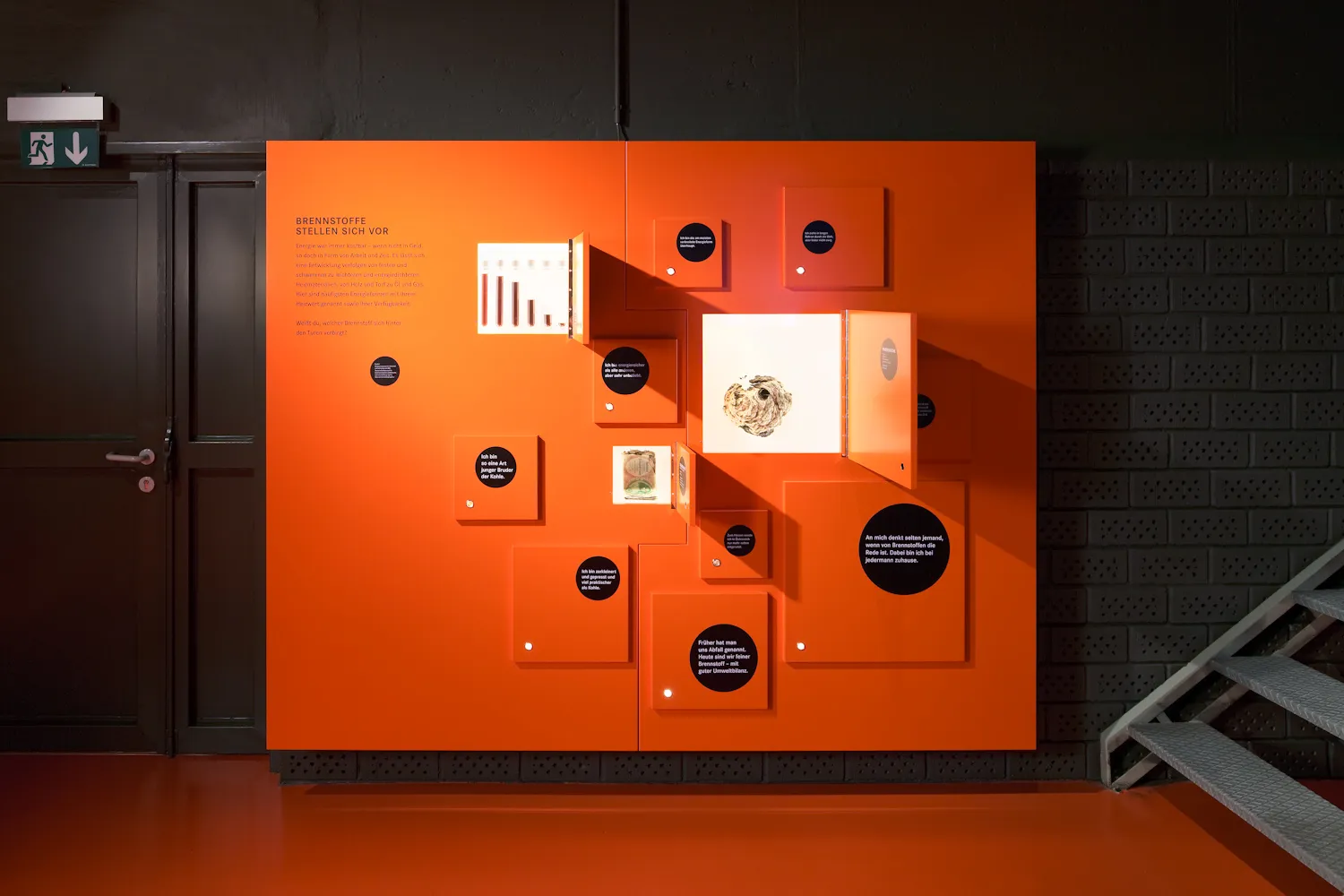 pared de exhibición naranja con varios paneles, artefactos y exhibiciones informativas en un entorno de museo