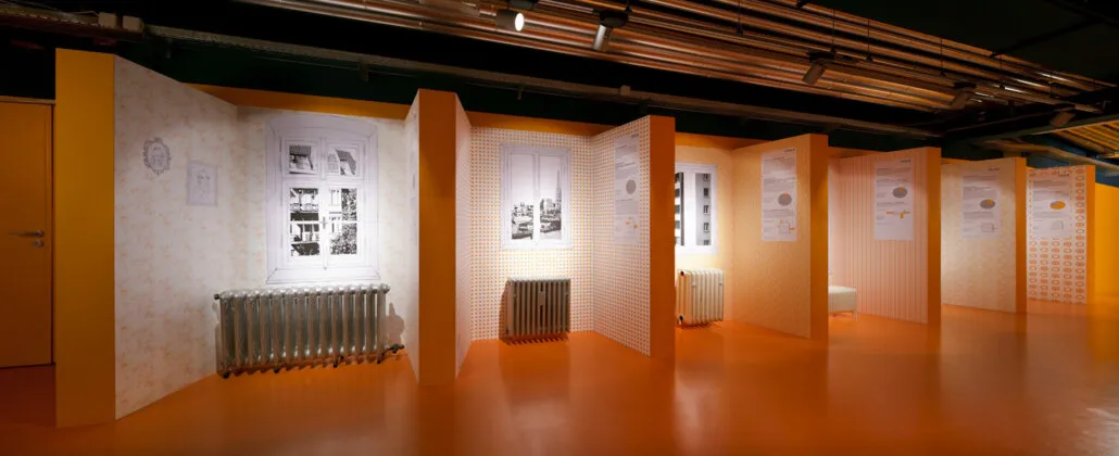Sala de exposiciones con paneles blancos, fotografías históricas y radiadores en exhibición