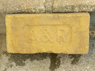 yellow brick with embossed initials A&R on a stone surface