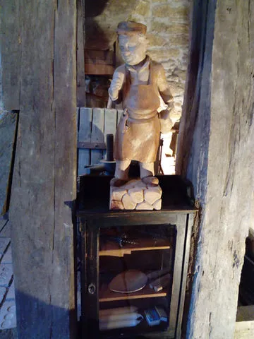 Wooden sculpture of a brickmaker on a cabinet in a stone-walled room