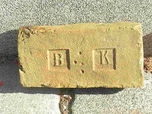 gele baksteen met de letters B en K in reliëf
