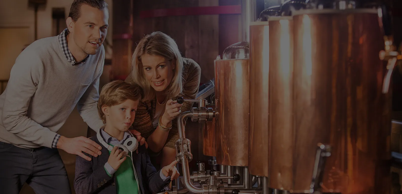 Een gezin van drie dat koperen brouwketels bekijkt bij een interactieve brouwerij-expositie