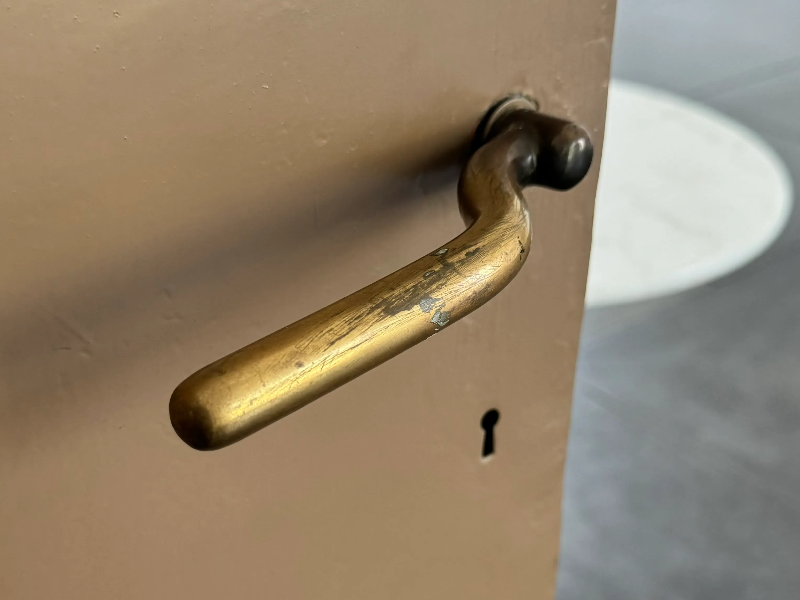 close-up van een messing deurklink en sleutelgat op een beige deur