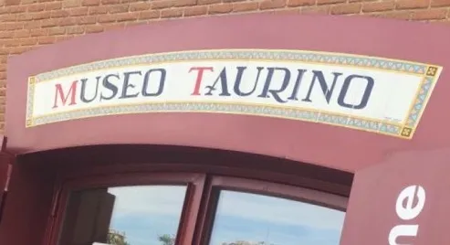 Arco de color granate con un letrero decorativo que dice 'MUSEO TAURINO' en letras rojas y negras