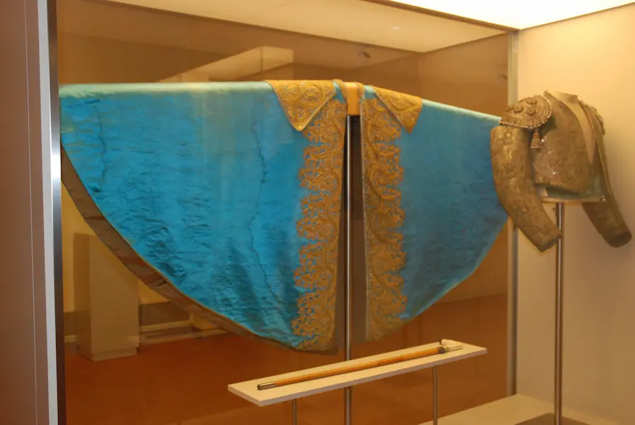 blauw en gouden stierenvechterskostuum in een glazen vitrine