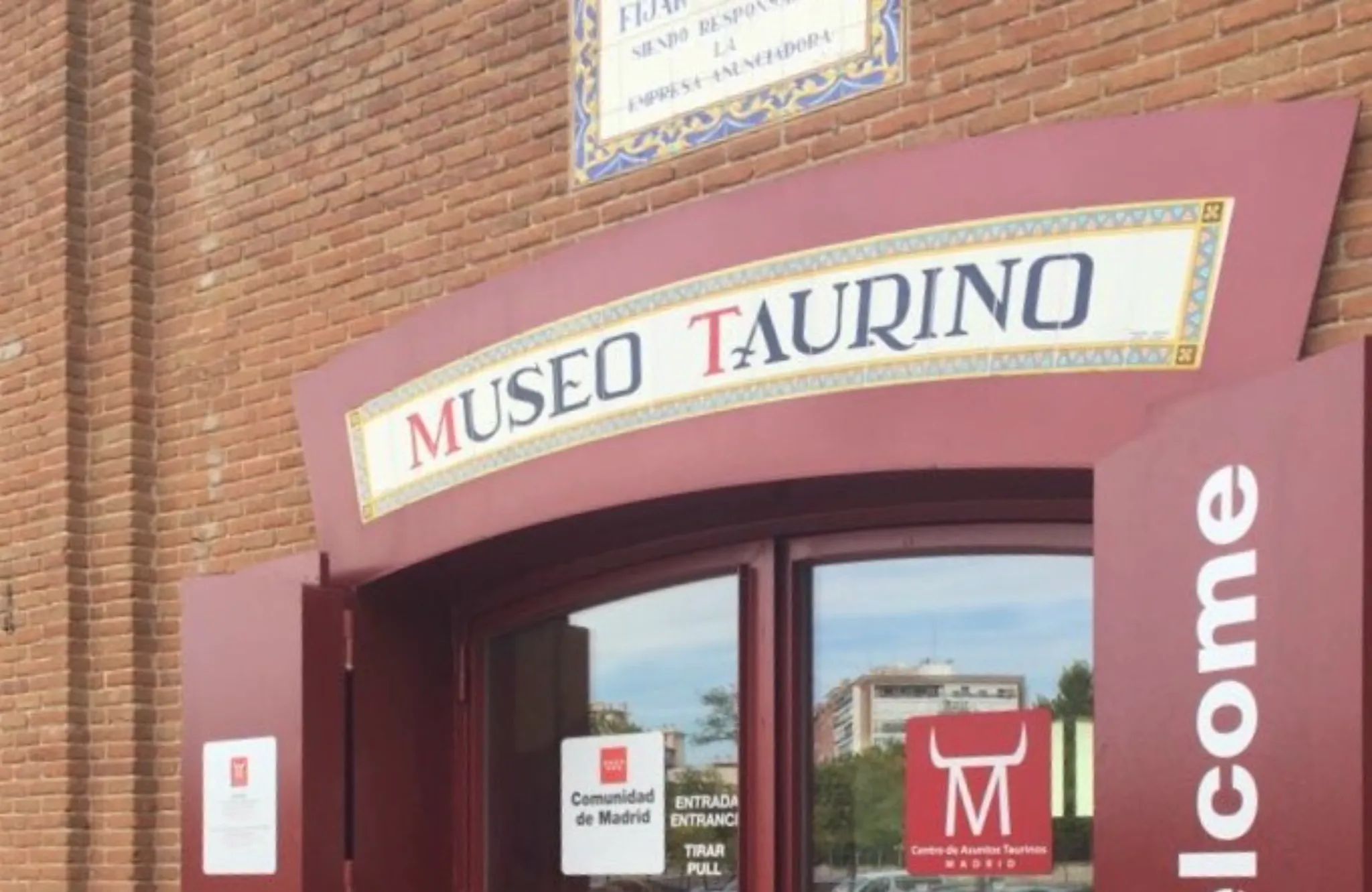 Edificio de ladrillo rojo con un letrero de entrada color burdeos que dice MUSEO TAURINO en letras blancas y azules.