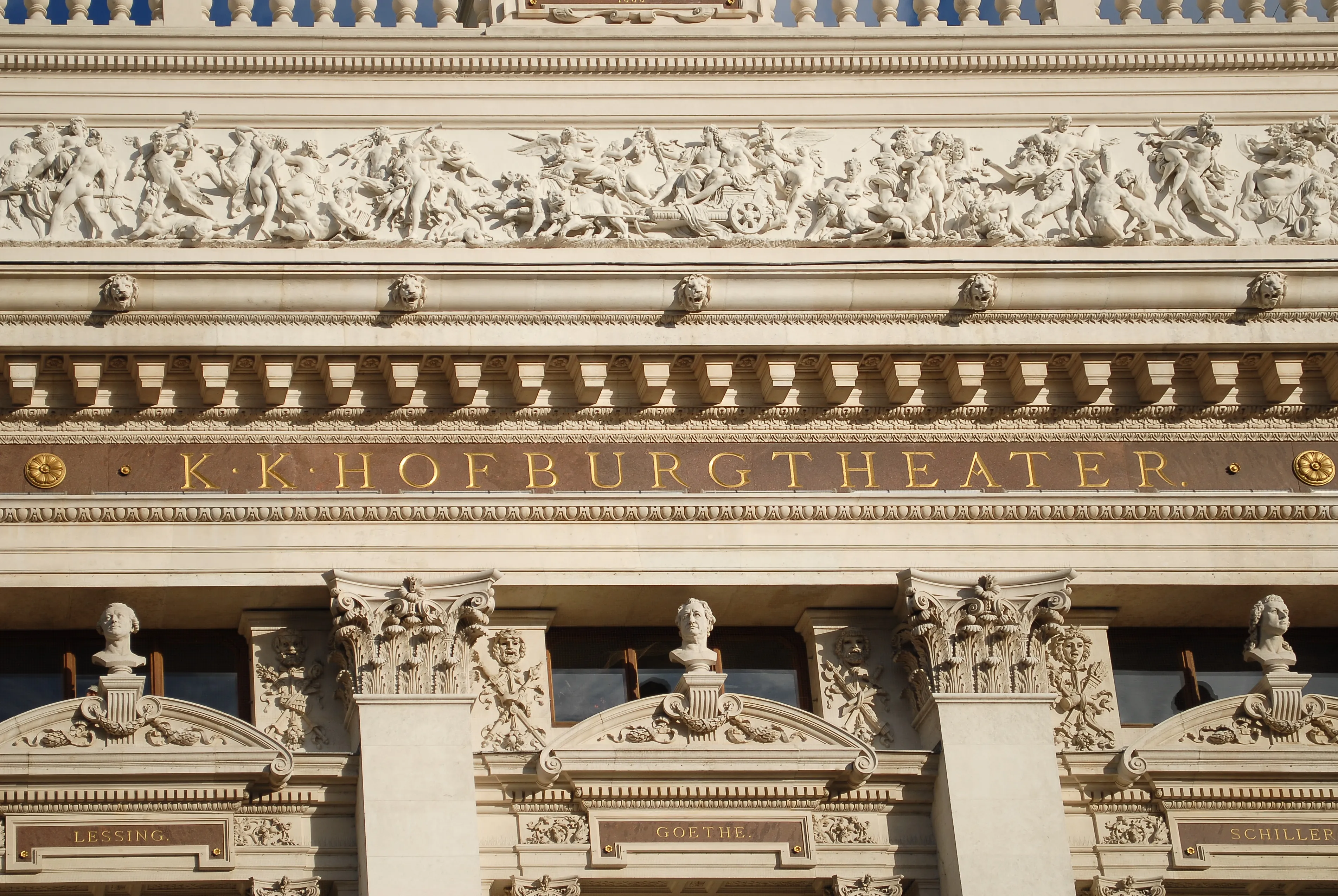 Close-up van de gevel van het Burgtheater met sierlijke gravures en gouden belettering