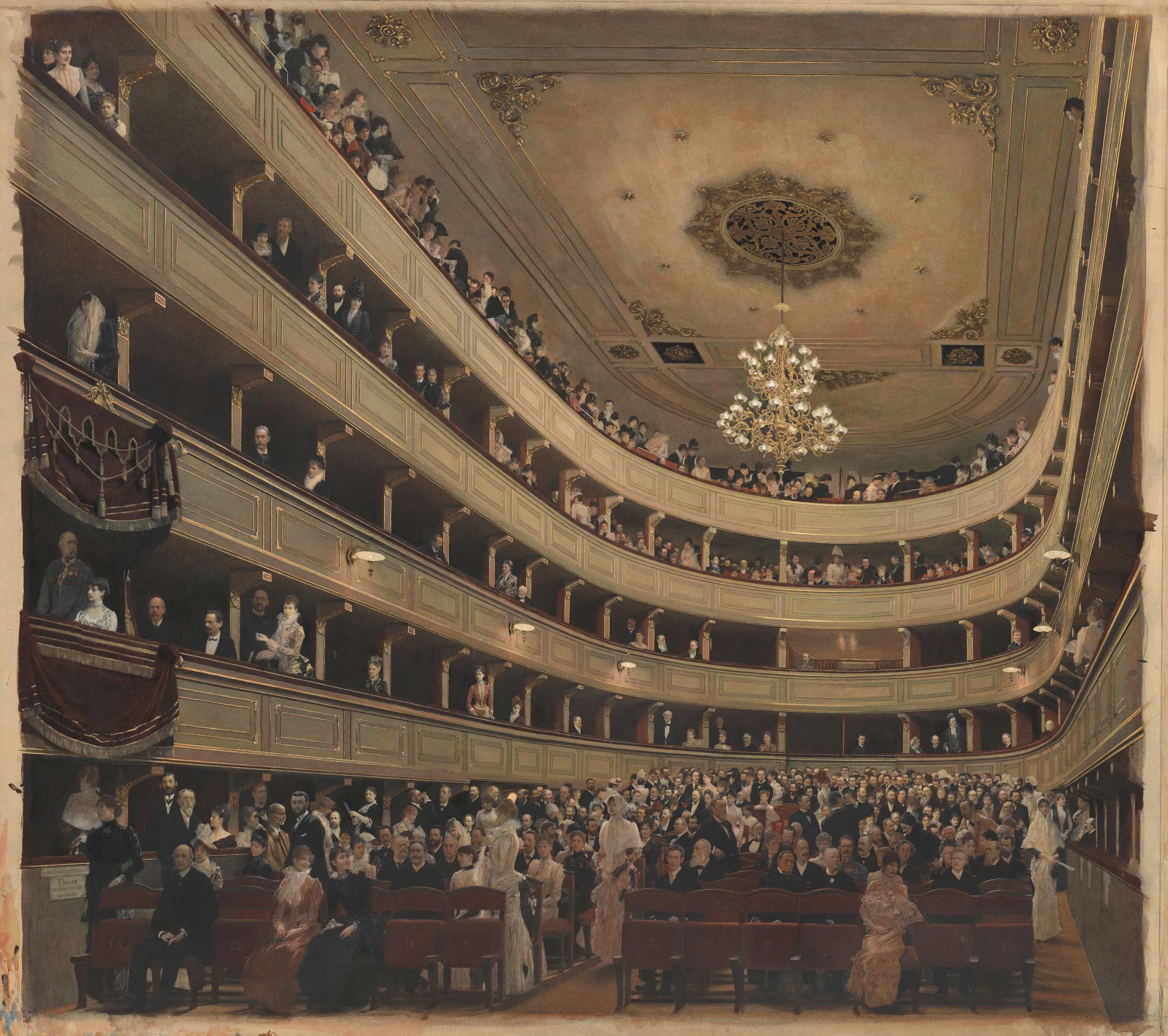 Ornaat theaterauditorium met meerdere balkonniveaus, een centrale kroonluchter en publiek in formele kleding.