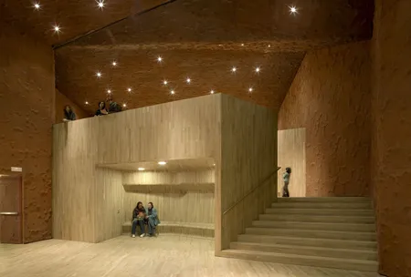 Interieur van CaixaForum Madrid met houten trap en zichtbare bakstenen muren