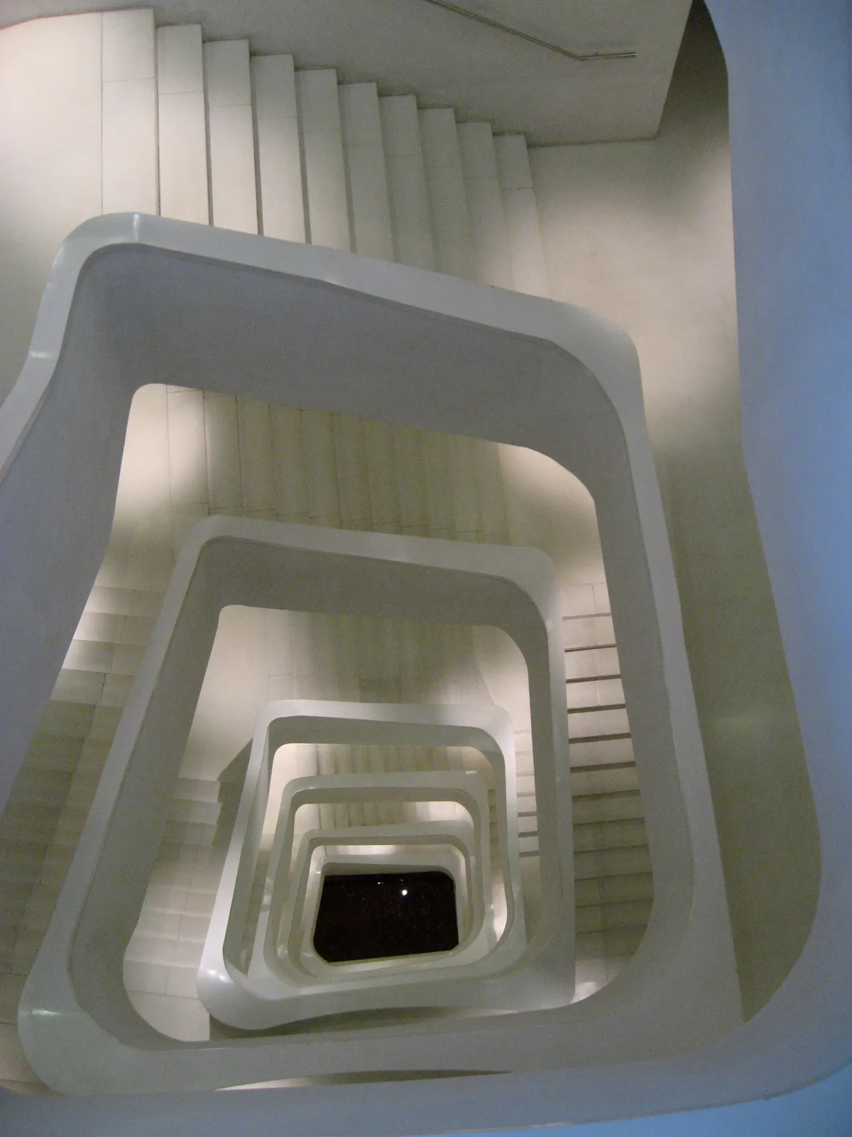 Een moderne witte spiltrap met geometrische balustrades van bovenaf gezien