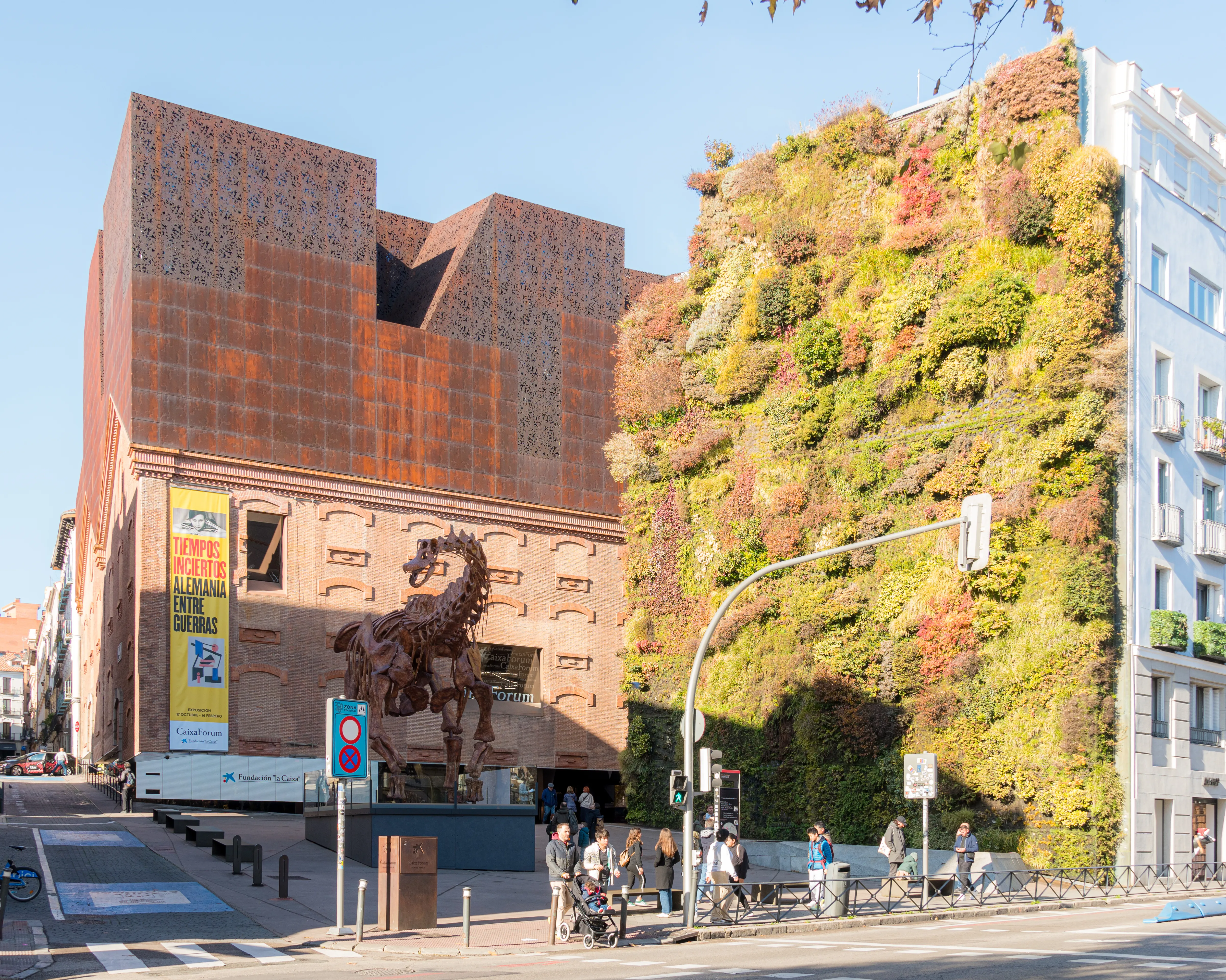 Het CaixaForum Madrid gebouw met een verticale tuin en een groot bronzen paardbeeld ervoor