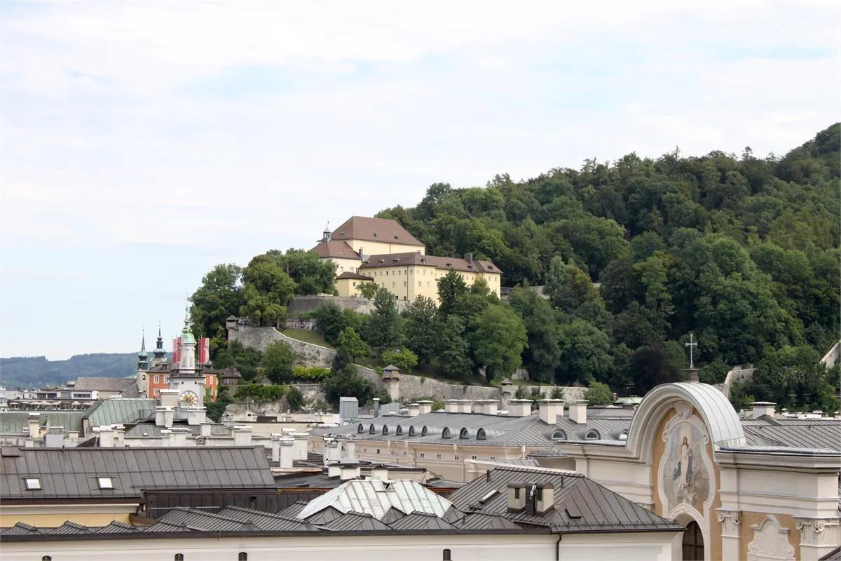 A distant view of the Capuchin Monastery situated on a wooded hill overlooking the rooftops of Salzburg.
