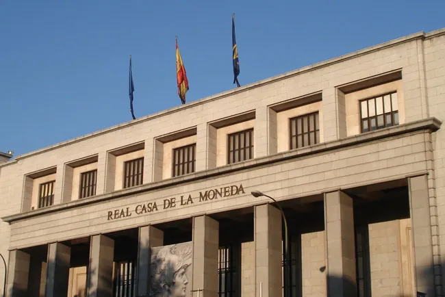 Zewnętrzna część Museo Casa de la Moneda z napisem nazwy na fasadzie i flagami powiewającymi nad nią.