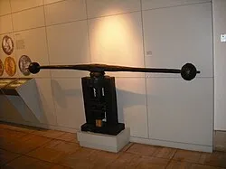 Una imprenta negra con una viga horizontal larga exhibida sobre un pedestal blanco en una galería de museo.
