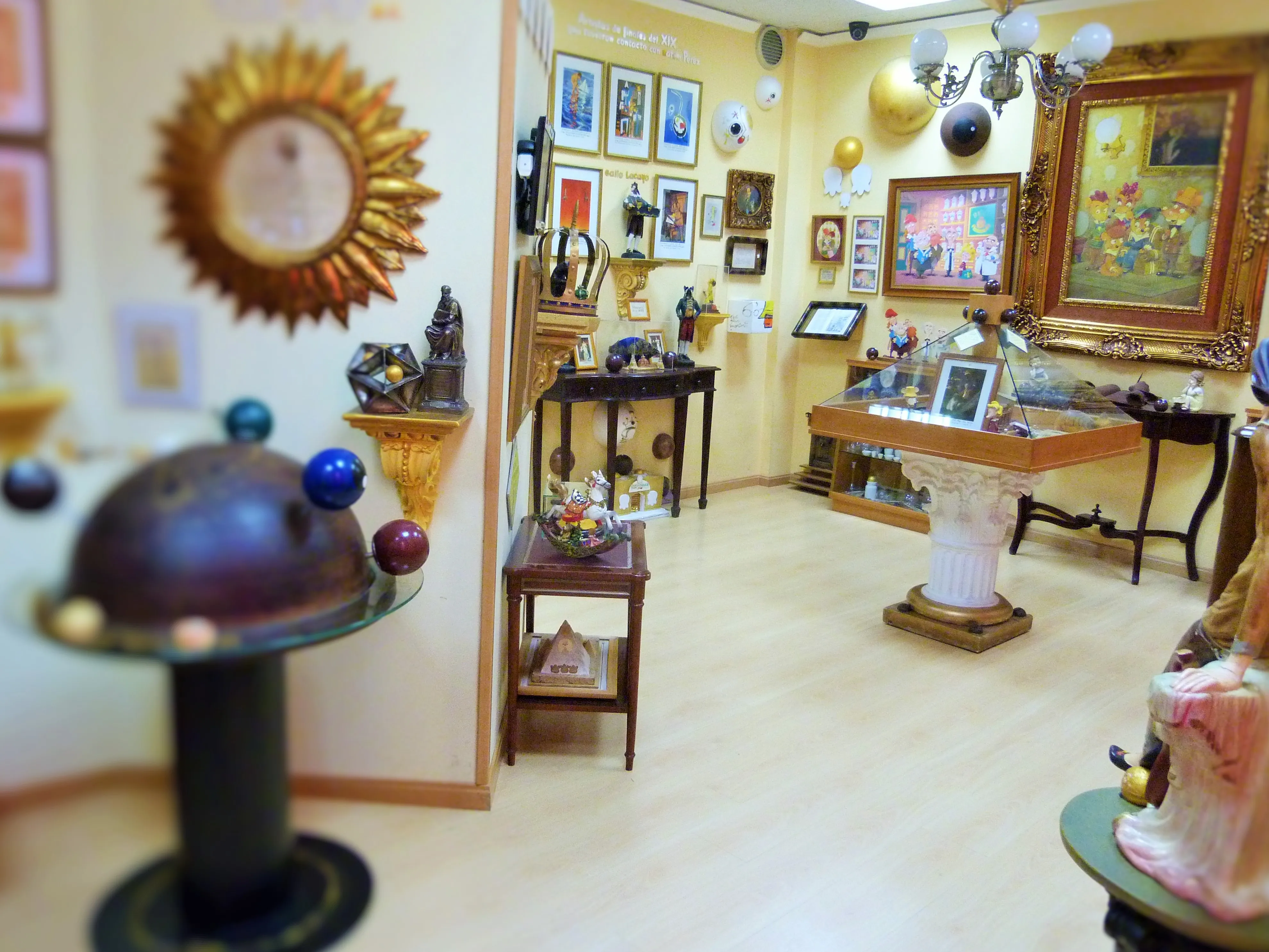 Interior de un museo con varias exhibiciones, incluyendo un gran globo terráqueo, un reloj de sol y obras de arte enmarcadas en las paredes.