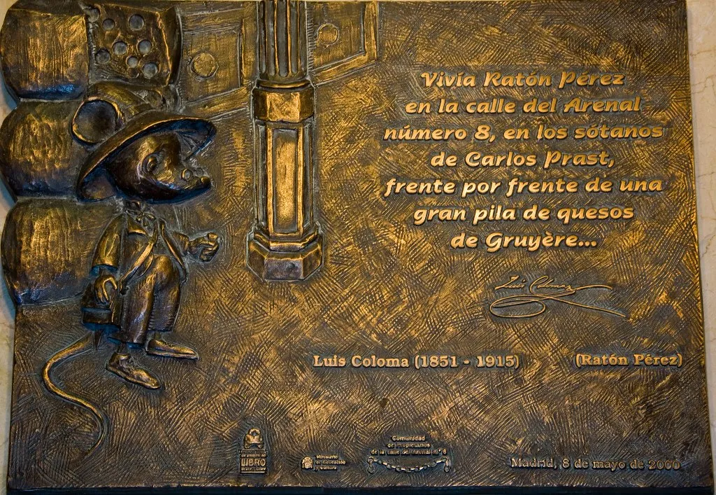 Placa de bronce con un relieve de un personaje ratón con sombrero y abrigo, de pie junto a un texto en español que describe la leyenda del Ratón Pérez.