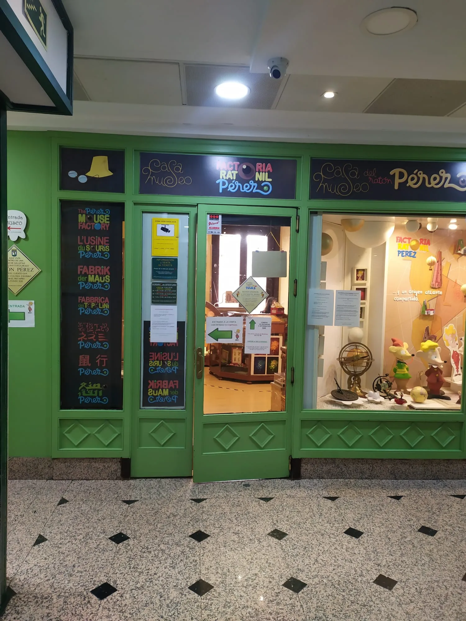 Fachada verde de Casa Museo Ratón Pérez con señalización colorida y un escaparate que muestra exposiciones del museo