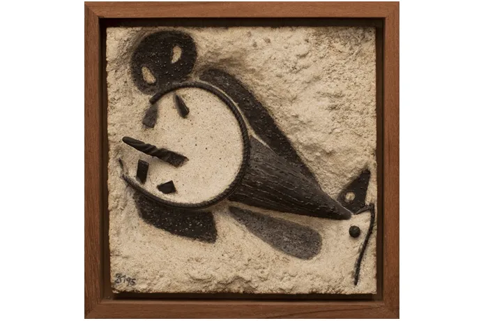 Una obra de arte en relieve enmarcada que presenta una esfera abstracta similar a un reloj de color negro con formas geométricas dispersas sobre un fondo de yeso beige texturizado, firmada en la esquina inferior izquierda.