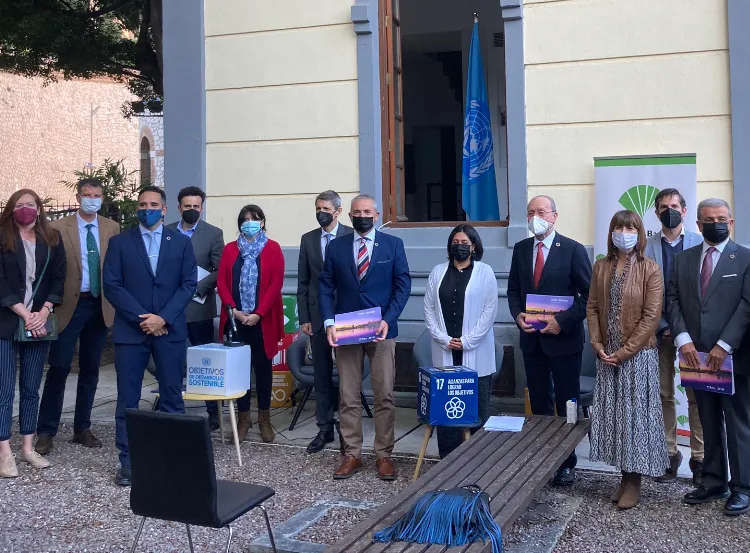 Grupo de personas con mascarillas de pie frente a un edificio con una bandera de las Naciones Unidas y un cartel de CIFAL, sosteniendo carpetas en un evento oficial