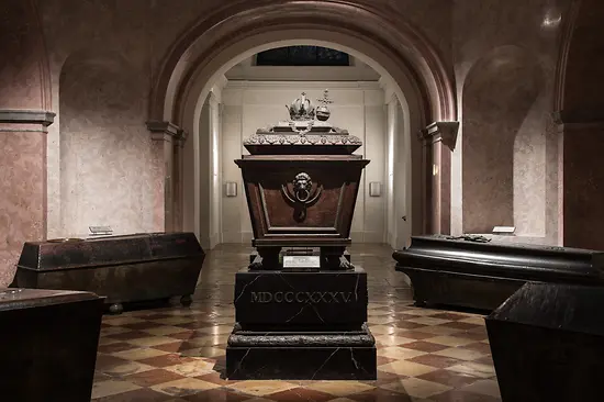 A large ornate tomb in a vaulted hall with arched ceilings and checkered flooring
