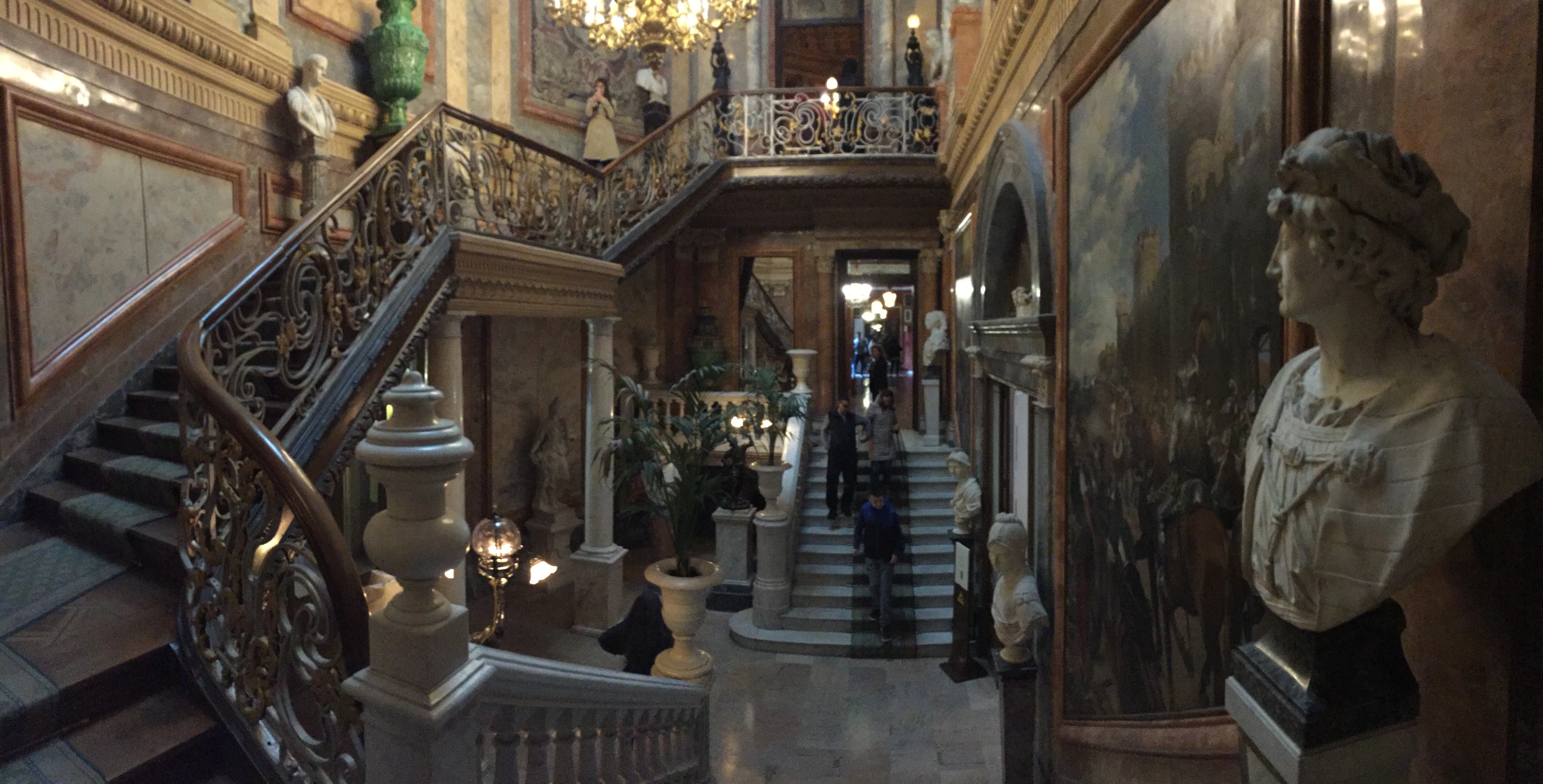 Ozdobne schody z żelaznymi balustradami i klasycznymi rzeźbami we wnętrzu Muzeum Cerralbo