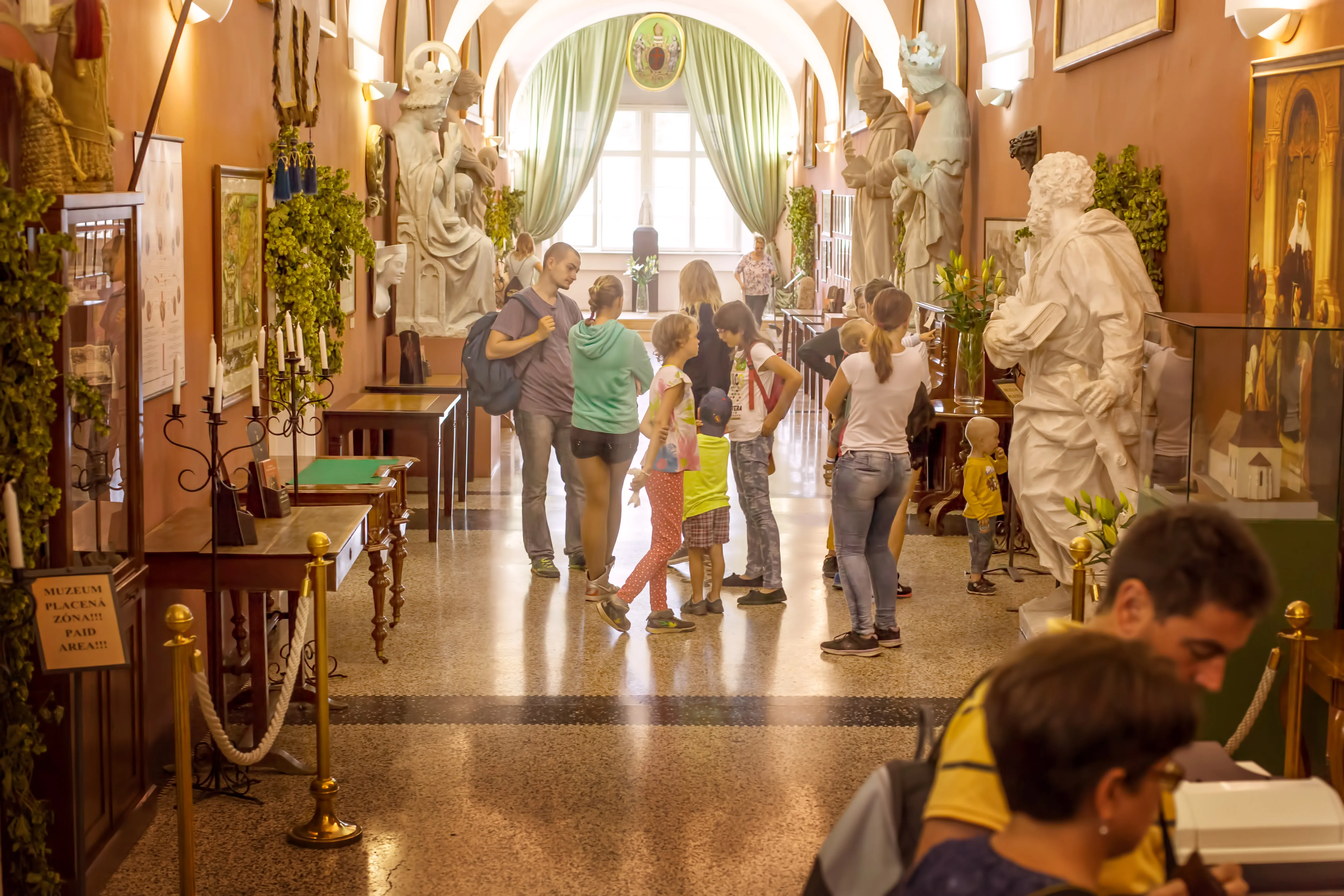 Groep bezoekers in een museumgang met beelden en tentoonstellingen