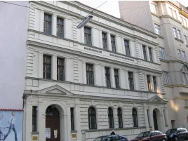Exterior de un edificio de color claro con ventanas arqueadas y una entrada central, identificado como el Museo de los Ramoneadores.