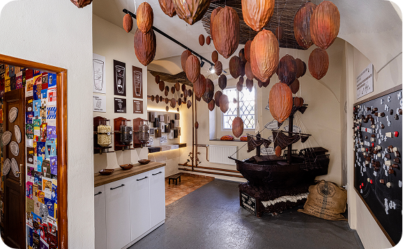 Interior of a museum with large chocolate bean sculptures hanging from the ceiling and a chocolate ship model on display