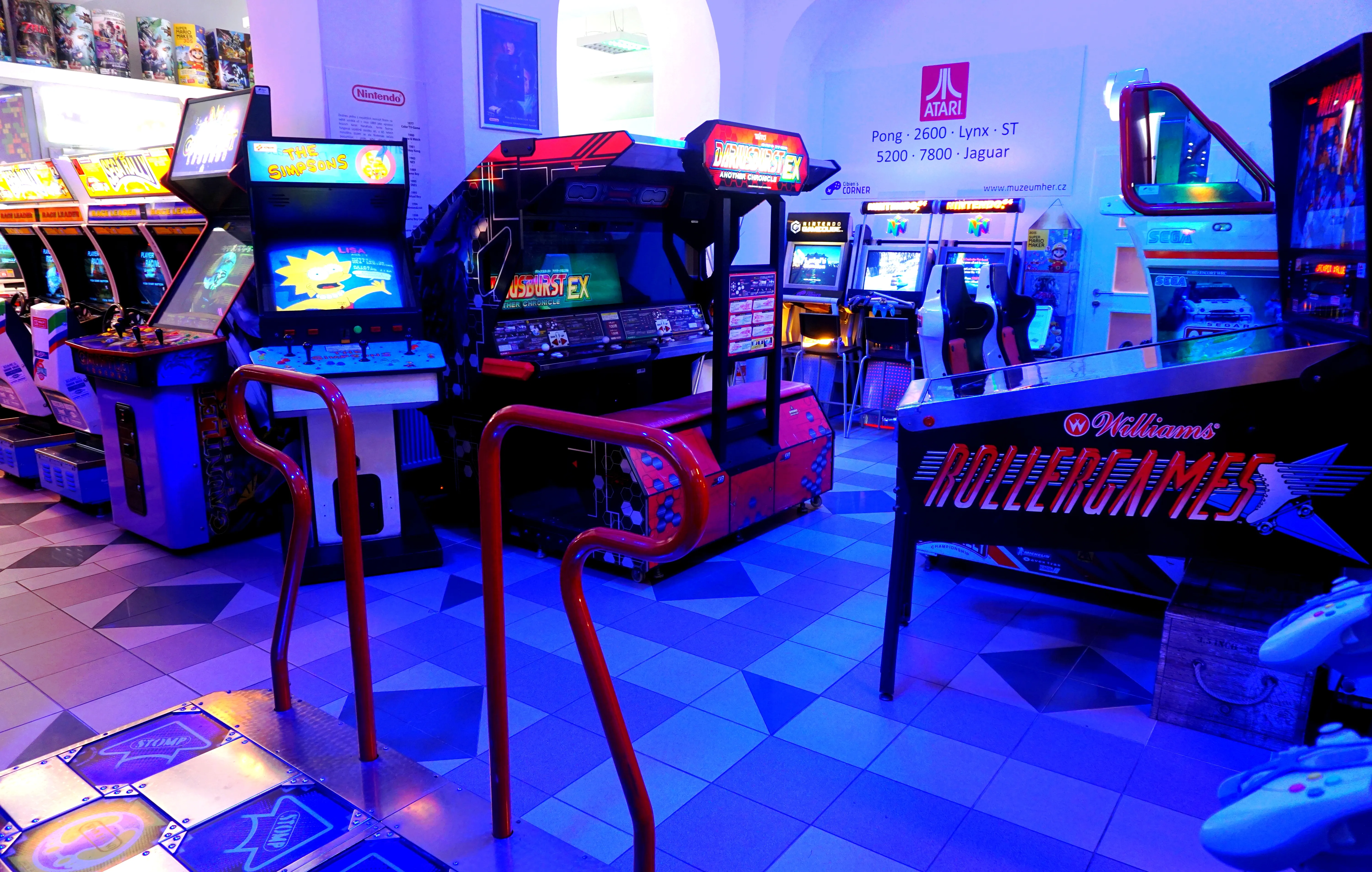 arcade machines and gaming consoles in a museum with blue lighting