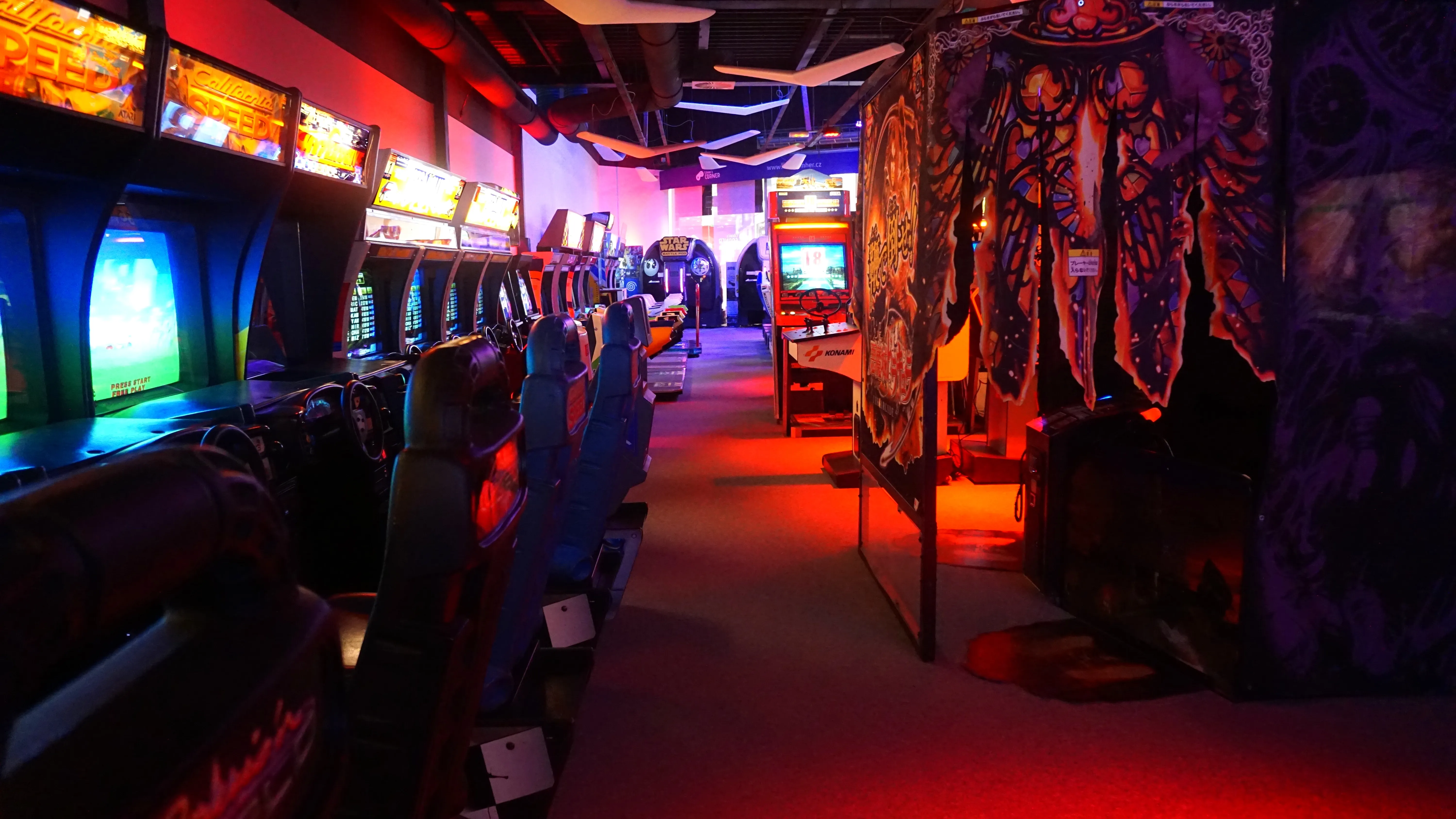 Rows of arcade machines with glowing screens and colorful lighting in a museum hallway