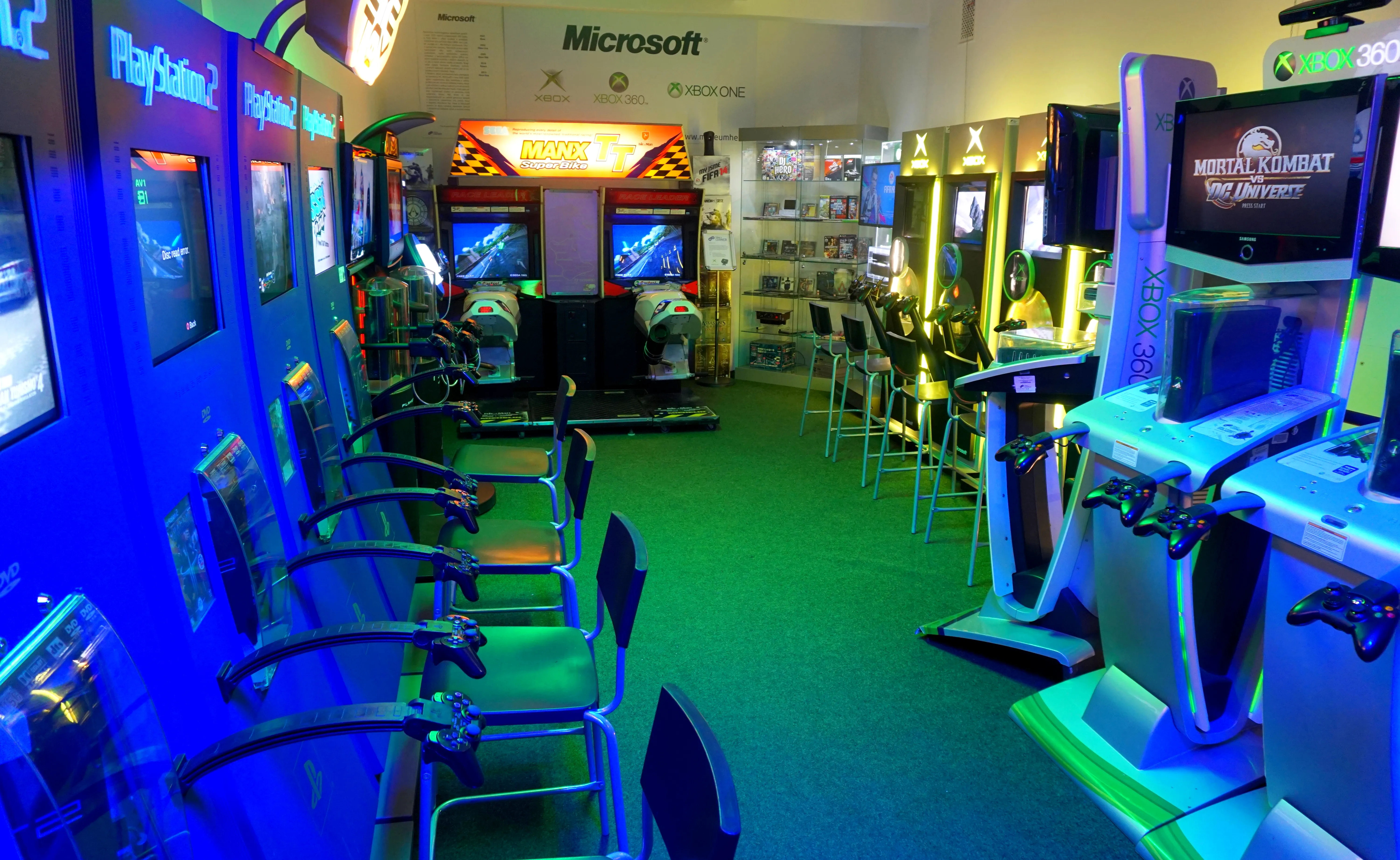 Interior of a video game museum with arcade machines and consoles under blue and green lighting