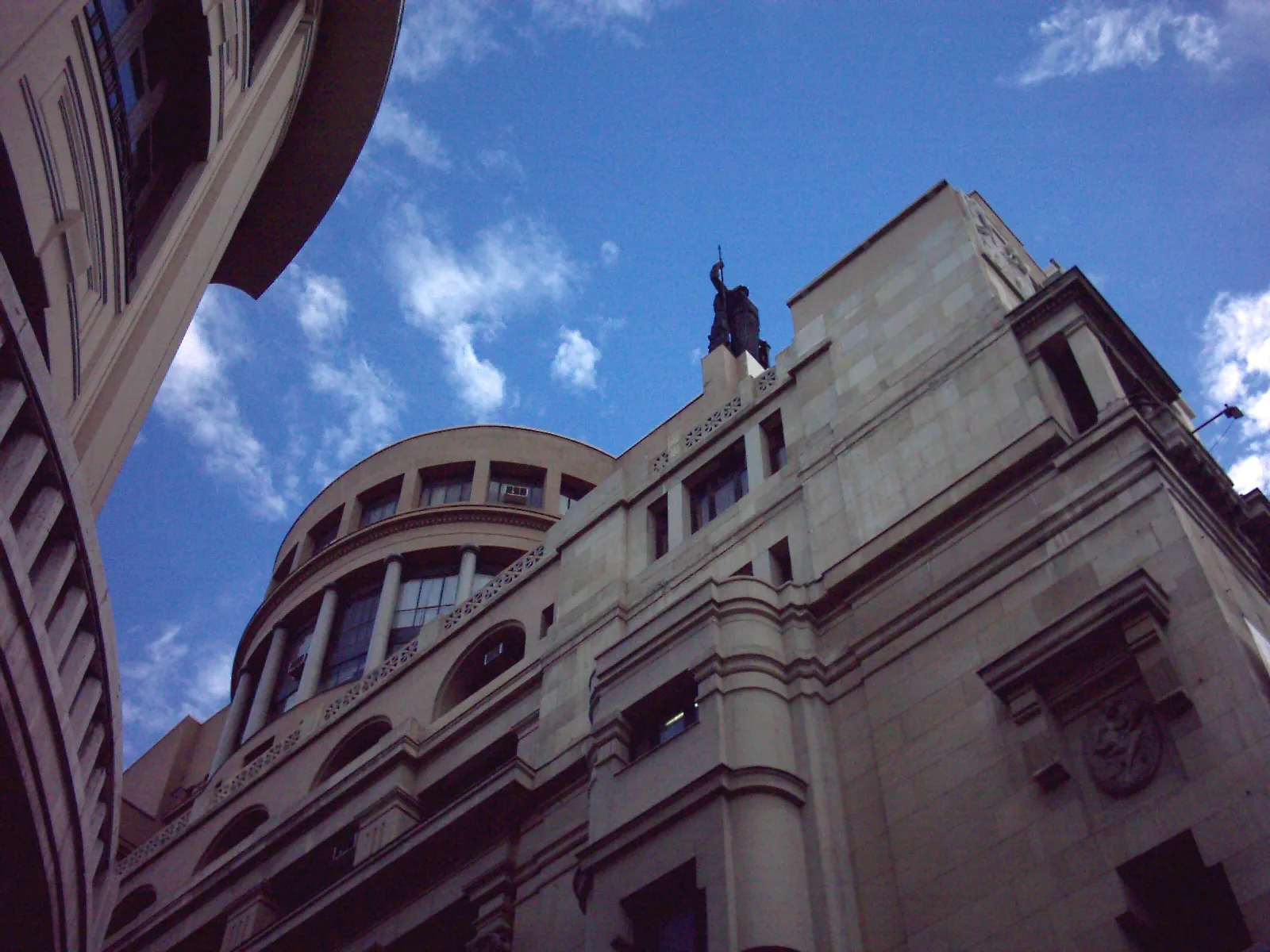Vista en picado del edificio del Círculo de Bellas Artes con una estatua en la azotea contra un cielo azul