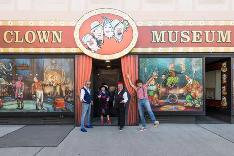 Entrada al Museo del Payaso de Viena con murales coloridos de payasos y gente posando delante