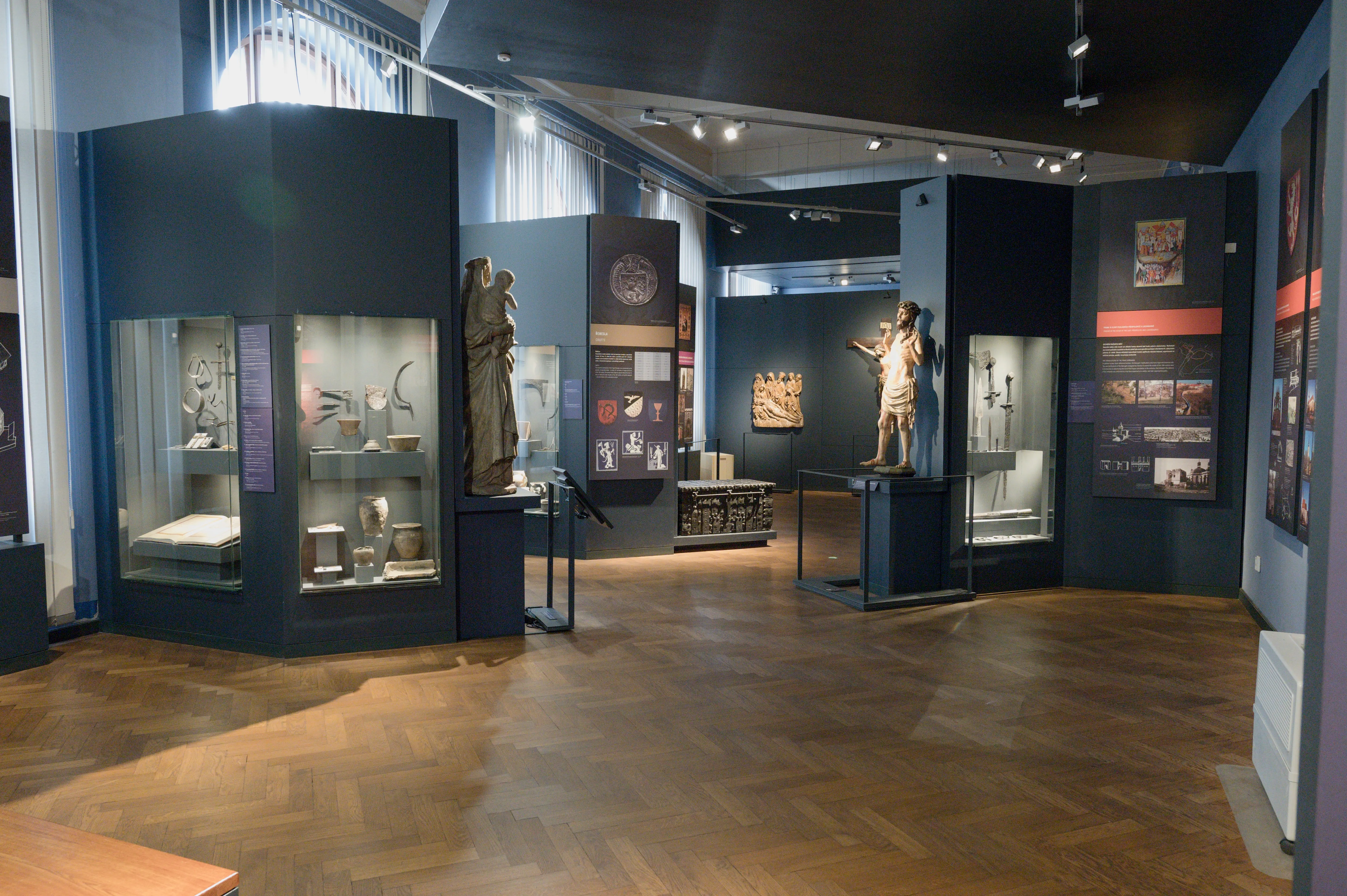 Exhibition hall with display cases, sculptures, and informational panels in a museum interior