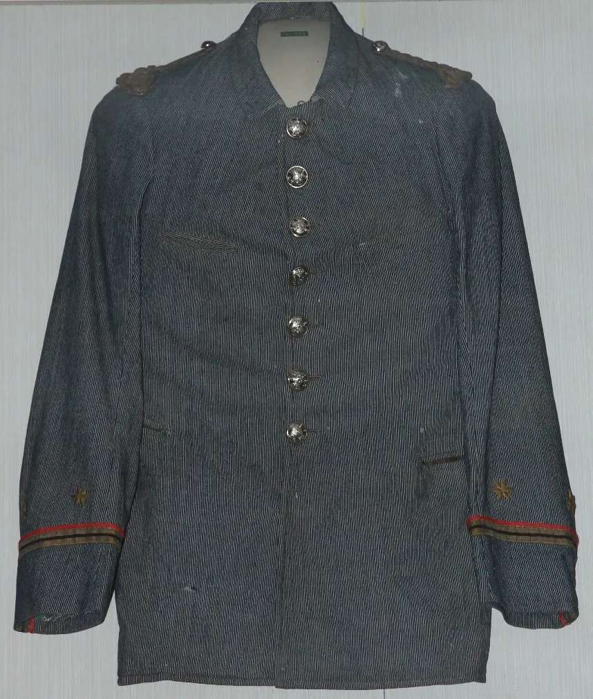 Een donkerblauw en wit gestreepte militaire uniform met zilveren knopen en insigne op de schouders en manchetten