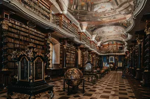Interior de una biblioteca barroca con techos altos, decoraciones ornamentadas y hileras de estanterías